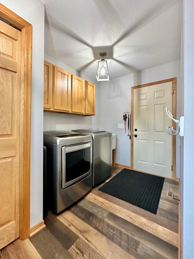 washroom with cabinets, a textured ceiling, and washing machine and clothes dryer