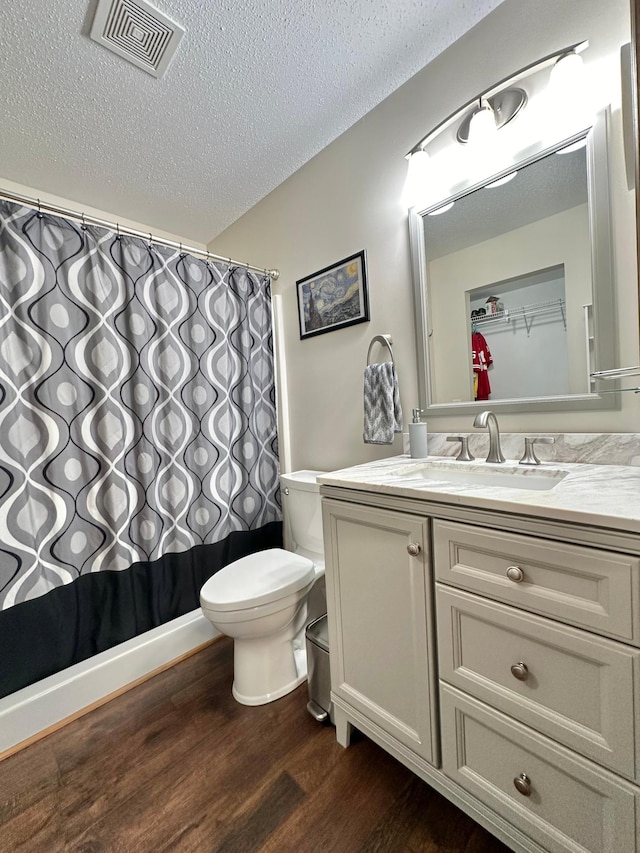 bathroom with walk in shower, hardwood / wood-style floors, a textured ceiling, toilet, and vanity