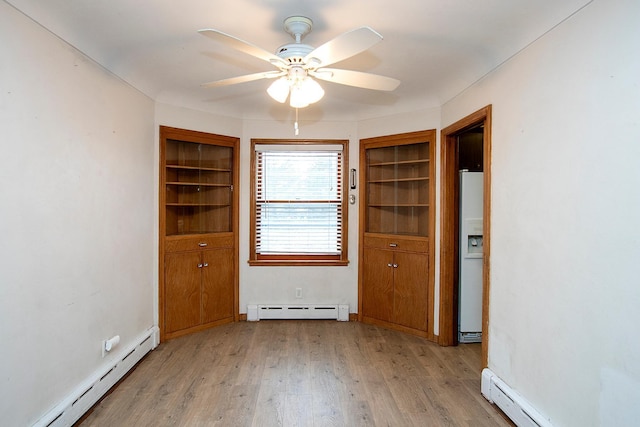 spare room featuring light hardwood / wood-style flooring, ceiling fan, and a baseboard heating unit