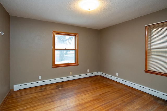 unfurnished room featuring light hardwood / wood-style floors, a textured ceiling, and a baseboard heating unit