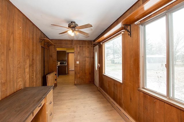 corridor with wooden walls and light hardwood / wood-style floors