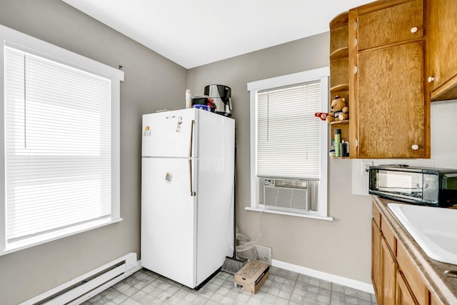 kitchen featuring sink, a baseboard heating unit, and white fridge