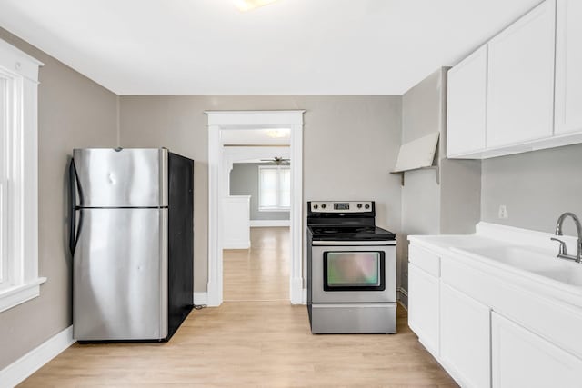 kitchen with appliances with stainless steel finishes, light hardwood / wood-style floors, white cabinetry, ceiling fan, and sink