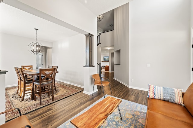 dining area with ornate columns, a notable chandelier, and dark wood-type flooring