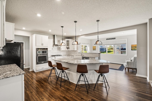 kitchen with appliances with stainless steel finishes, wall chimney exhaust hood, dark hardwood / wood-style flooring, and white cabinetry