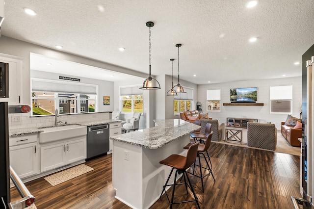 kitchen with a breakfast bar, dishwasher, a center island, and white cabinetry