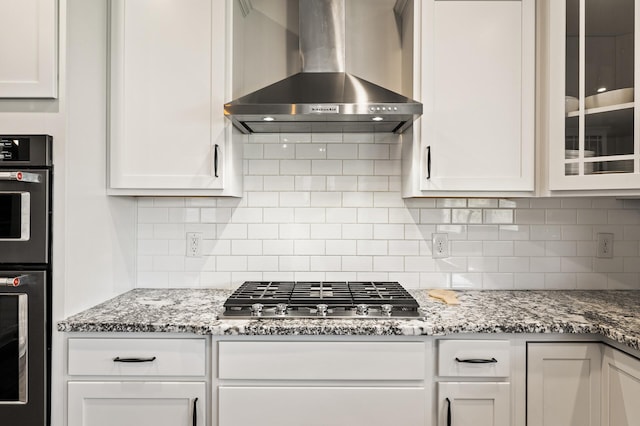 kitchen with white cabinets, stainless steel appliances, and wall chimney range hood