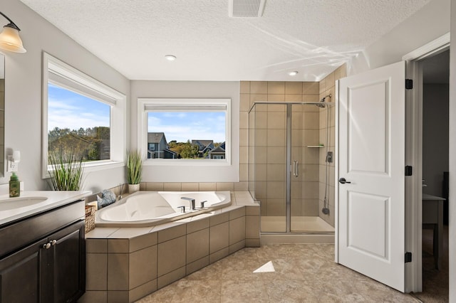 bathroom with a textured ceiling, a healthy amount of sunlight, vanity, and shower with separate bathtub