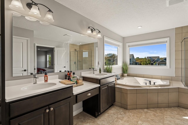 bathroom with a textured ceiling, independent shower and bath, vanity, and tile patterned floors