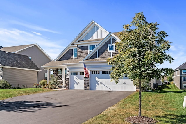 craftsman-style home with cooling unit, a front yard, and a garage