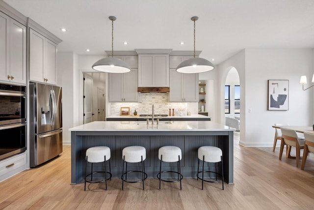 kitchen featuring appliances with stainless steel finishes, a center island with sink, and pendant lighting