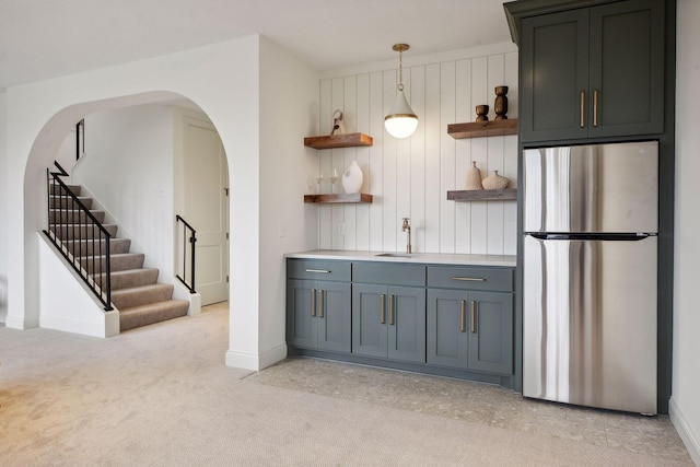 kitchen with light carpet, sink, hanging light fixtures, and stainless steel fridge