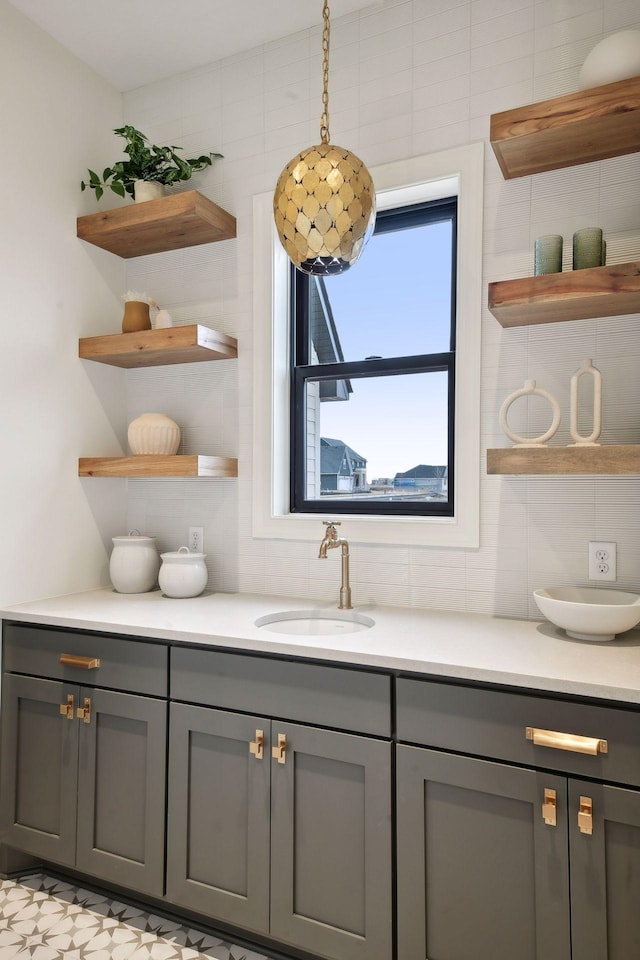 interior space featuring sink, decorative light fixtures, backsplash, gray cabinets, and tile walls