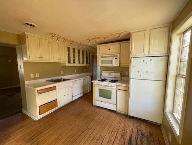 kitchen with track lighting, dark wood-type flooring, sink, white cabinets, and white appliances