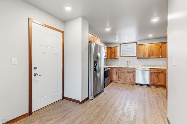 kitchen featuring light wood-style flooring, appliances with stainless steel finishes, light countertops, and brown cabinetry