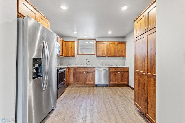 kitchen featuring a sink, light countertops, light wood-type flooring, recessed lighting, and stainless steel appliances