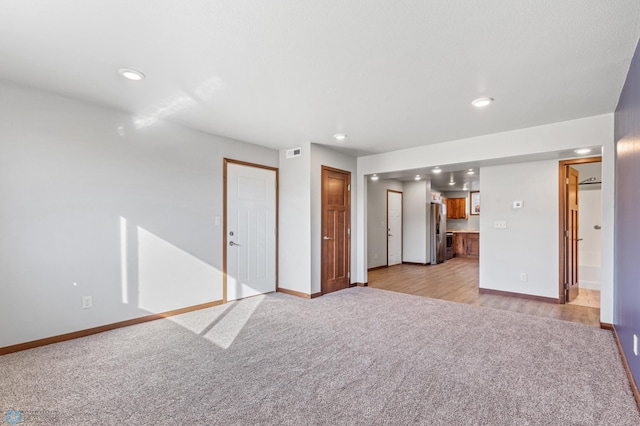 unfurnished living room featuring light carpet, baseboards, visible vents, and recessed lighting