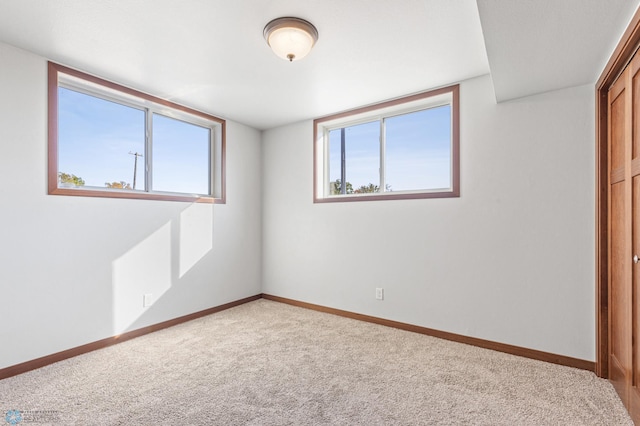 unfurnished bedroom with a closet, baseboards, multiple windows, and light carpet