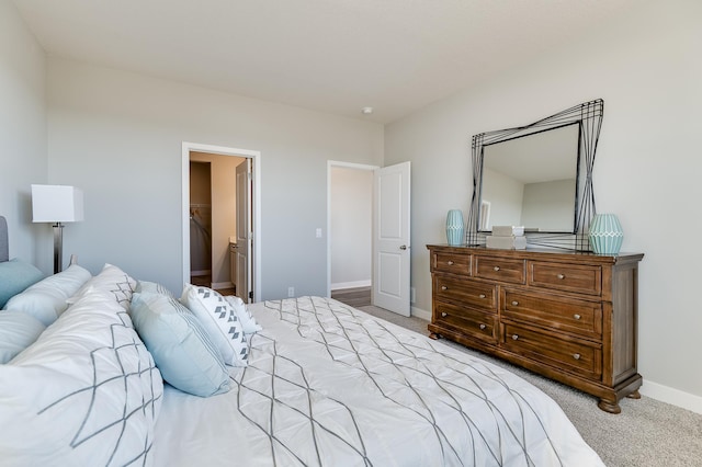 bedroom featuring a spacious closet, a closet, and light colored carpet