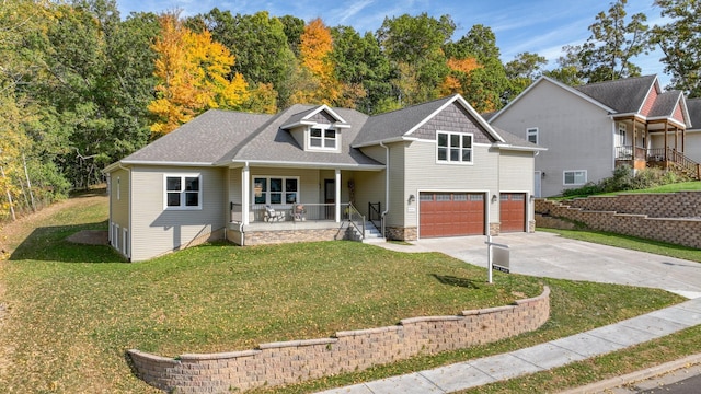 view of front property with covered porch, a garage, and a front yard