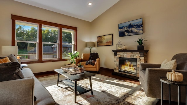 sitting room with hardwood / wood-style floors, a stone fireplace, and vaulted ceiling