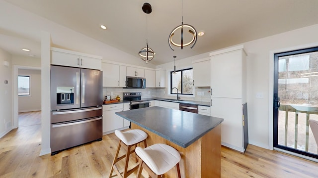 kitchen with sink, white cabinets, backsplash, hanging light fixtures, and stainless steel appliances