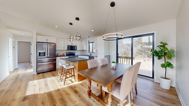 dining area featuring vaulted ceiling, sink, and light hardwood / wood-style flooring