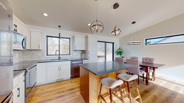 kitchen featuring white cabinetry, appliances with stainless steel finishes, a center island, and sink