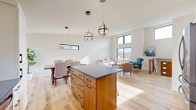 kitchen featuring stainless steel refrigerator, a center island, hanging light fixtures, and light wood-type flooring