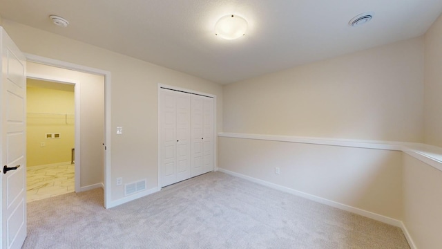 unfurnished bedroom featuring light colored carpet and a closet