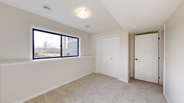 unfurnished bedroom with light carpet and a closet