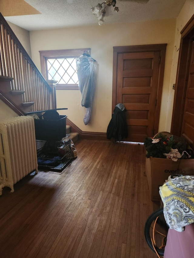 foyer featuring radiator, a textured ceiling, and dark wood-type flooring