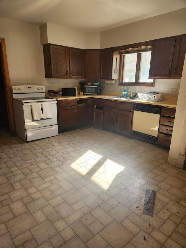 kitchen featuring dark brown cabinetry, sink, and white appliances