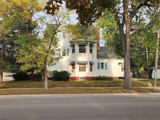 view of front of home with roof with shingles and a front lawn