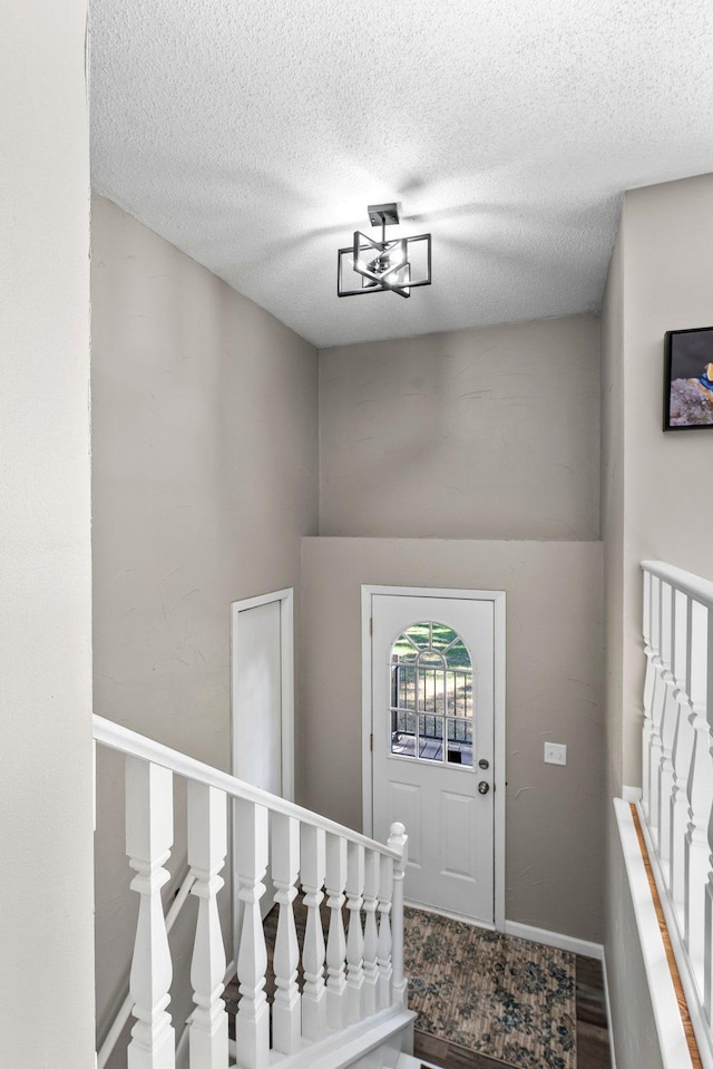 foyer entrance featuring a notable chandelier, a textured ceiling, and hardwood / wood-style flooring