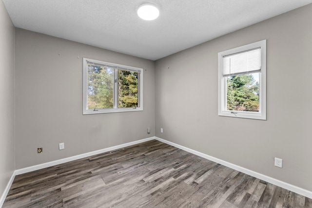 unfurnished room with dark wood-type flooring, a textured ceiling, and a healthy amount of sunlight