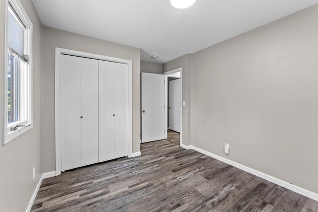 unfurnished bedroom featuring a textured ceiling, a closet, and dark hardwood / wood-style floors