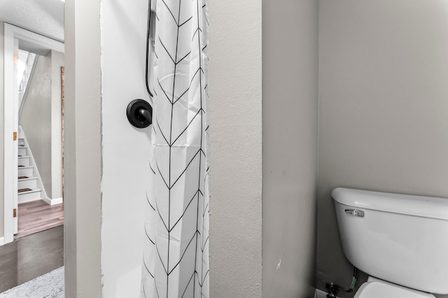 bathroom with wood-type flooring, walk in shower, and toilet