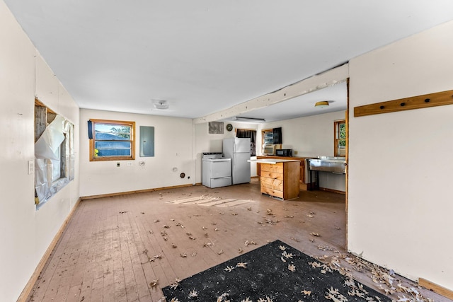 kitchen featuring white appliances, light hardwood / wood-style floors, electric panel, and washing machine and dryer