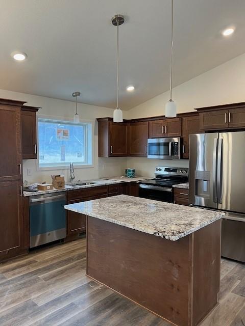 kitchen with decorative light fixtures, stainless steel appliances, lofted ceiling, and sink