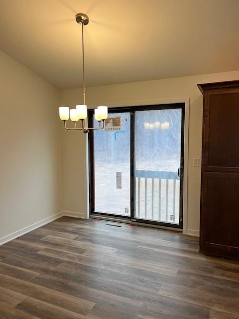 unfurnished dining area featuring dark wood-type flooring and a notable chandelier