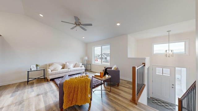 living room with hardwood / wood-style flooring, ceiling fan with notable chandelier, and high vaulted ceiling