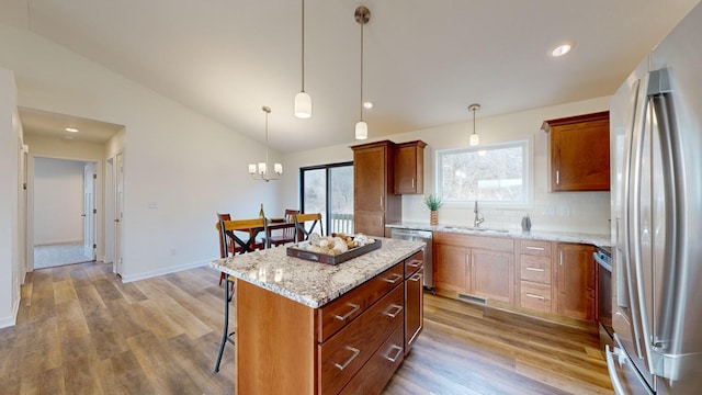 kitchen with lofted ceiling, sink, a center island, appliances with stainless steel finishes, and pendant lighting