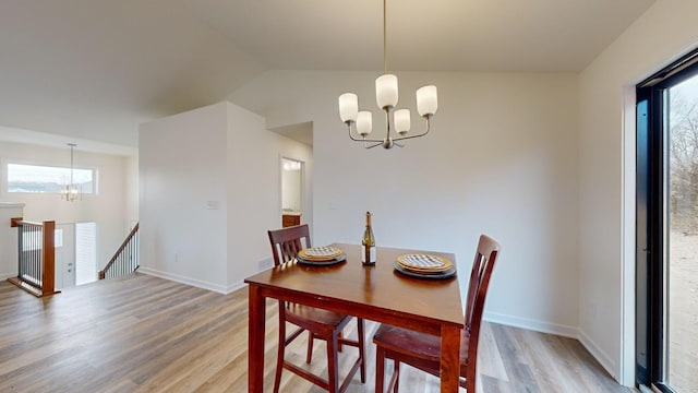 dining space featuring an inviting chandelier, lofted ceiling, and hardwood / wood-style flooring