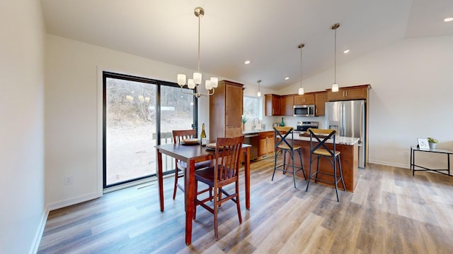 dining area featuring high vaulted ceiling, sink, an inviting chandelier, and light hardwood / wood-style flooring