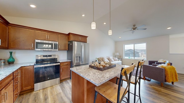 kitchen featuring hanging light fixtures, appliances with stainless steel finishes, a kitchen breakfast bar, and light hardwood / wood-style flooring