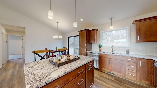 kitchen with a kitchen island, lofted ceiling, sink, hanging light fixtures, and stainless steel dishwasher