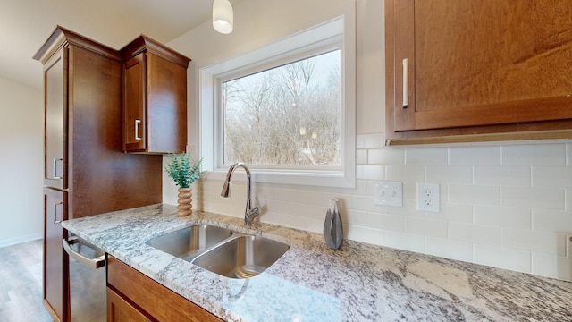 kitchen featuring sink, light stone counters, tasteful backsplash, light hardwood / wood-style flooring, and stainless steel dishwasher