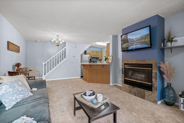 living room featuring a fireplace, a textured ceiling, light carpet, and a notable chandelier