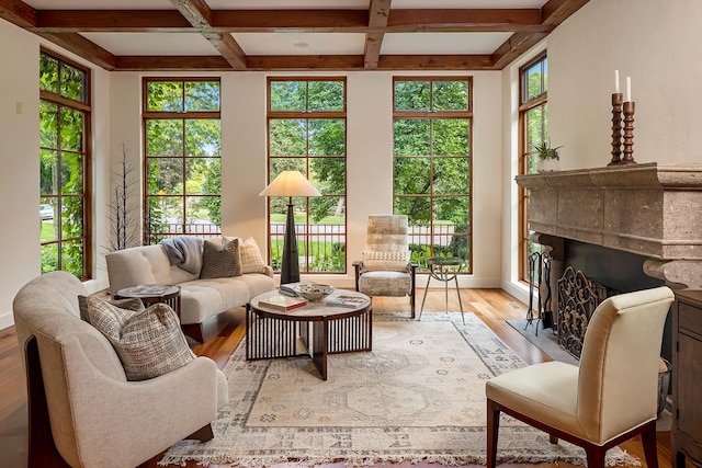 living room with beam ceiling, coffered ceiling, plenty of natural light, and light hardwood / wood-style flooring